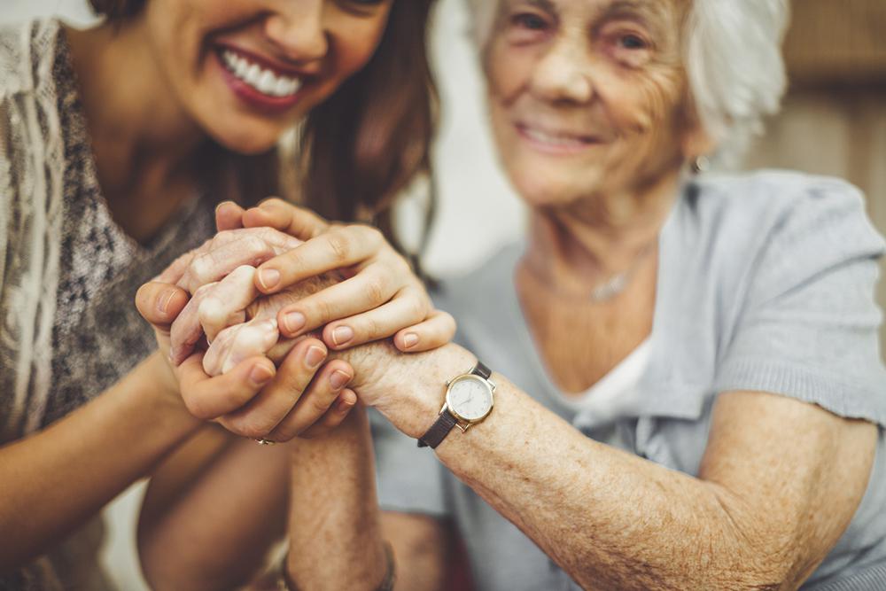 adult woman holding hands with her mother who is wearing a medical alert